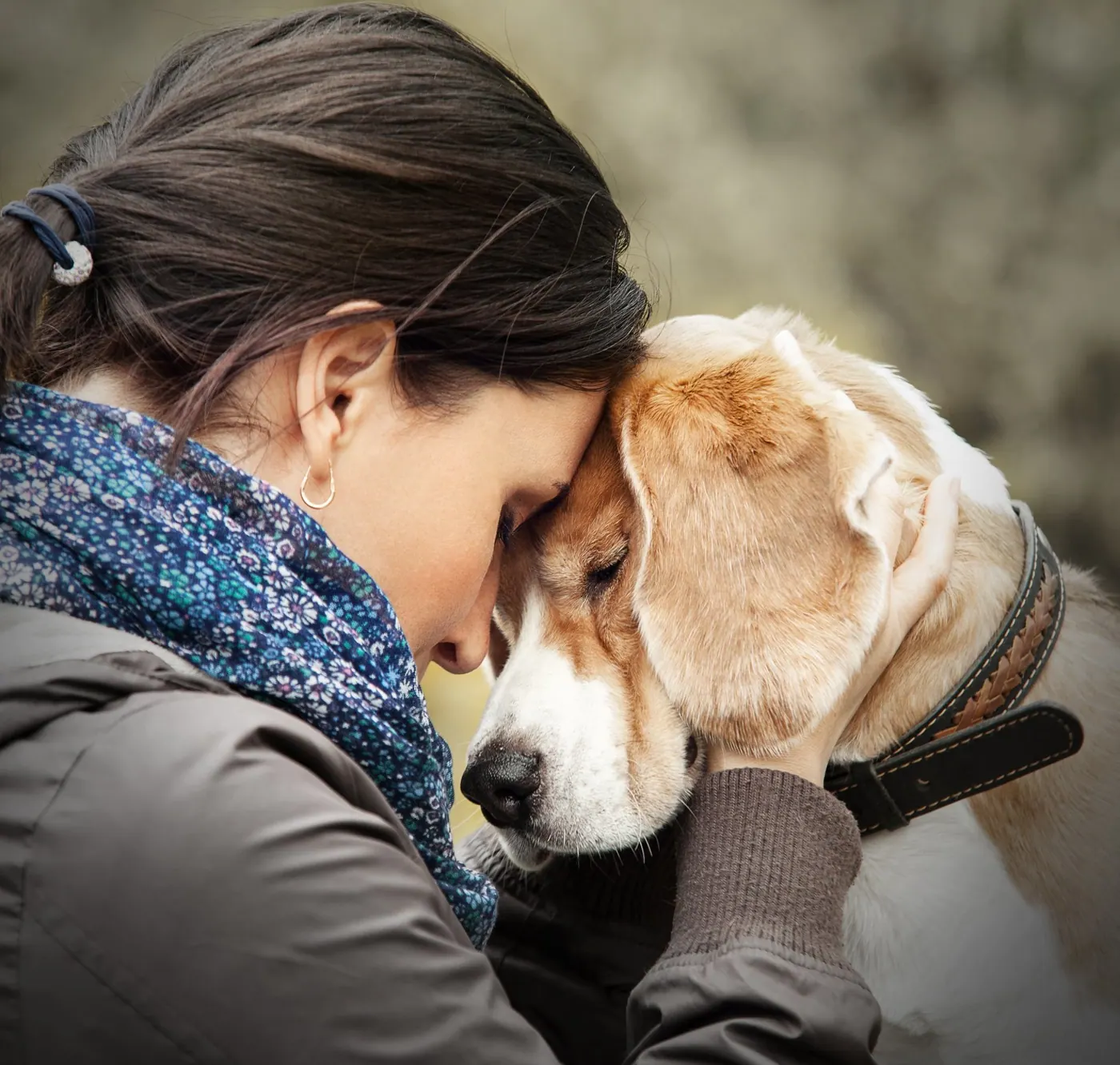 Woman resting her head against her dog in a warm hug